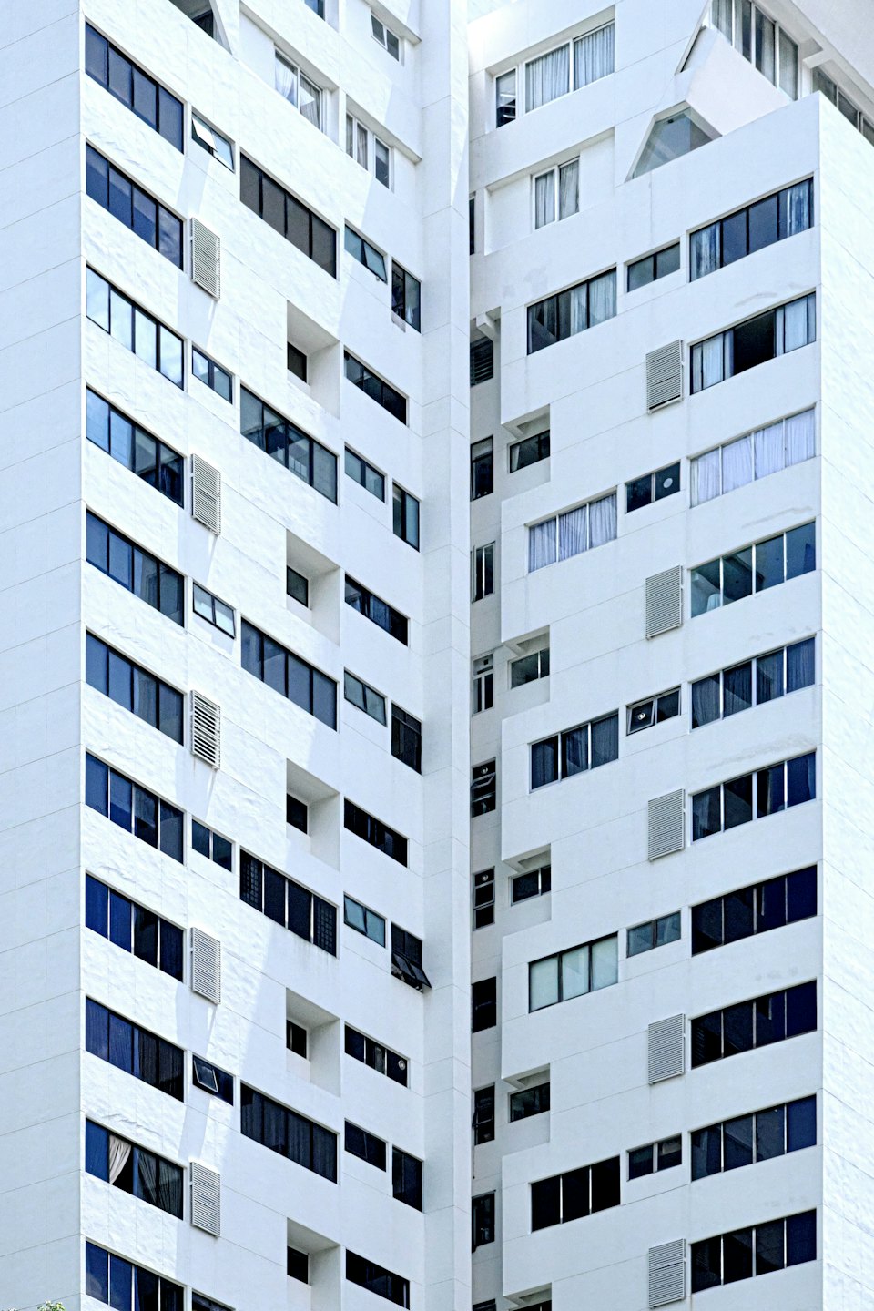 Modern white apartment building with grid of dark windows.